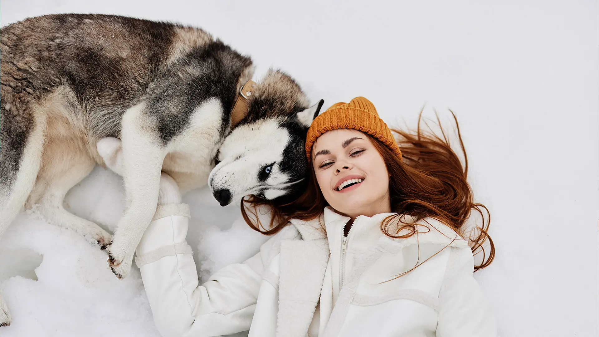 Hund und Frau kuscheln im Schnee